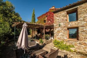 an umbrella and chairs in front of a stone house at Villa la Finca in Montferrer