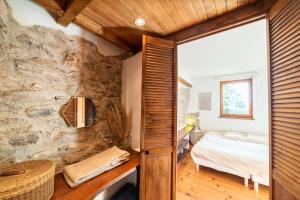 1 dormitorio con pared de piedra, cama y ventana en Villa la Finca, en Montferrer