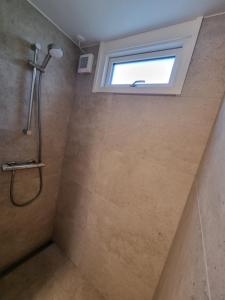 uma casa de banho com um chuveiro e uma janela em Slottets Anneks em Rønne
