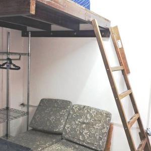 a loft bed with a couch and a ladder at Tiny House da Tata in Florianópolis