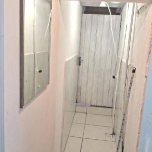a bathroom with a shower with a mirror and a tile floor at Tiny House da Tata in Florianópolis