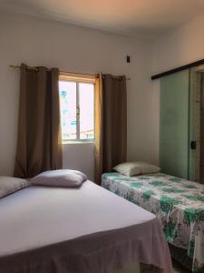 two beds in a room with a window at CASA PARA VISITANTES E ROMARIAS DA NOSSA SRA. DE APARECIDA in Aparecida