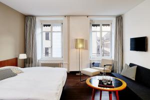 ein Hotelzimmer mit einem großen Bett und einem Tisch in der Unterkunft Krafft Basel in Basel