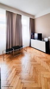 ein Wohnzimmer mit Holzboden und einem großen Fenster in der Unterkunft Appartement Cervantes 13 in Wien