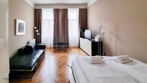 ein Schlafzimmer mit 2 Betten, einem Sofa und einem TV in der Unterkunft Appartement Cervantes 13 in Wien