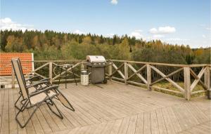 a grill and chairs on a wooden deck with trees at 3 Bedroom Pet Friendly Apartment In Deje in Deje