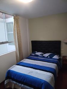 Un dormitorio con una cama azul y blanca y una ventana en Venecia Hotel Carrion, en Trujillo