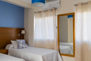 1 Schlafzimmer mit 2 Betten und einem Spiegel in der Unterkunft Hostal Imperial in Merida