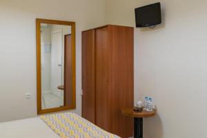 Zimmer mit einem Spiegel, einem kleinen Tisch und einem TV in der Unterkunft Hostal Imperial in Merida