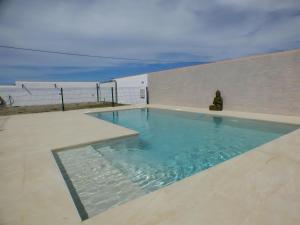 ein Schwimmbad mit einer Person, die neben einer Wand sitzt in der Unterkunft Casa rural Majadales piscina privada alta calidad in Conil de la Frontera