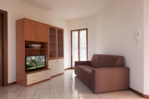 ein Wohnzimmer mit einem Sofa und einem TV in der Unterkunft Appartamento al Sole in Colà di Lazise