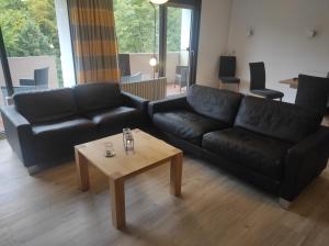 uma sala de estar com um sofá preto e uma mesa de centro em Ferienwohnung Fynns PeerLe em Bad Harzburg