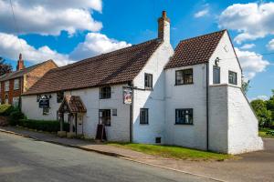 a white building on the side of a street at White Rose Cottages, Near Thirsk in Thirsk