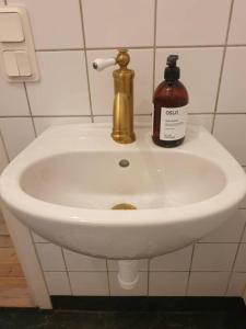 a bathroom sink with a bottle of soap on it at Centrala stan Hel 2 rums Gästsvit in Umeå