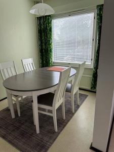 a dining room table and chairs with a table and a window at Welcomly apartment MILA in Kotka