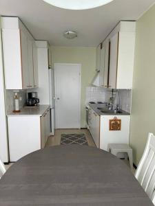 una cocina con armarios blancos y una mesa. en Welcomly apartment MILA, en Kotka