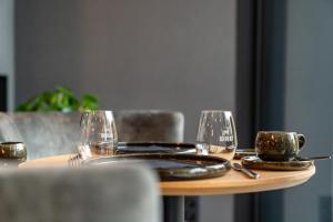 a table with two glasses and a plate and a cup at Aux Etangs - Hôtel in Battice