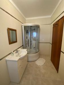 a white bathroom with a shower and a sink at Quinta Da Amoreira in Ferreira do Alentejo
