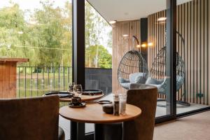 un restaurant avec une table, des chaises et une grande fenêtre dans l'établissement Aux Etangs - Hôtel, à Battice