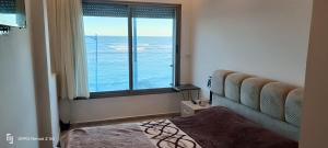 a bedroom with a window with a view of the ocean at Appartement Ilyas in El Jadida