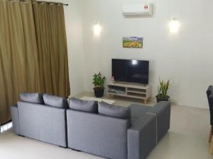 uma sala de estar com um sofá e uma televisão em Pinang Beach Home @ Ferringhi em Batu Ferringhi