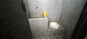 La salle de bains est pourvue de toilettes et d'un mur carrelé. dans l'établissement OYO 93295 Wisma Aluh Ambak, 