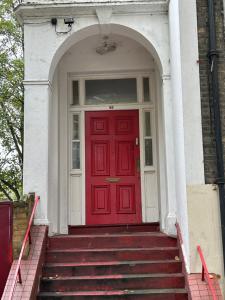 a red door on a white house with stairs at Cozy studio in London