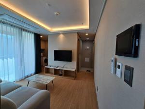 sala de estar con sofá y TV de pantalla plana en Gunamro Hotplace, en Busan