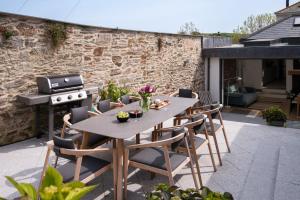 a patio with a table and chairs and a grill at The Printworks in Salcombe