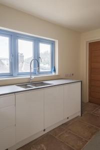 a white kitchen with a sink and two windows at The Edge in Dartmouth