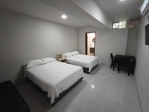 a bedroom with two beds and a desk and a table at Amaca Hostal in Santa Cruz de la Sierra