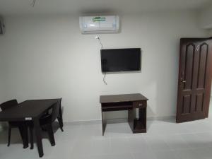 a room with a table and a tv on a wall at Amaca Hostal in Santa Cruz de la Sierra