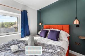 a bedroom with a bed with an orange headboard and purple pillows at Contractors Accommodation South Wales By Rutland Stays Short Lets & Serviced Accommodation Pentre in Treorky