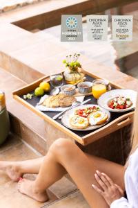 a woman sitting on the floor with a tray of food at Chromata Assos Villas Kefalonia in Asos