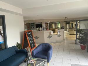 a living room with a blue couch and a kitchen at Brit Hotel La Bonne Etape in Évreux