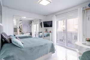 a white bedroom with a bed and a balcony at Silver horizon Luxury apartment in Nerja