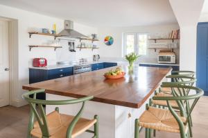 cocina con mesa de madera y 2 sillas verdes en White Horses en Salcombe