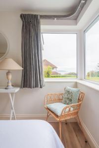 1 dormitorio con silla y ventana en White Horses en Salcombe