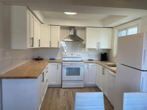 a white kitchen with white appliances and wooden floors at Spacious 3 bedroom apartment close Fairview! in Kitchener