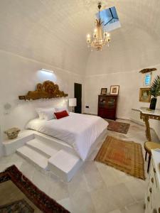 a bedroom with a white bed and a chandelier at Si Brahim studio piscine, Sidi Bou Saïd in Sidi Bou Saïd