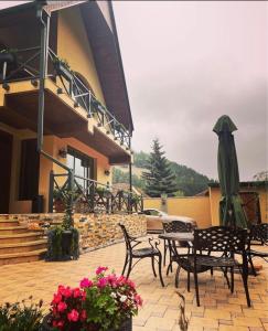 un patio con sillas, sombrilla y flores en Hotel Villa Alexander Dilijan, en Dilijan