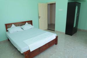 Bett mit weißer Bettwäsche und Kissen in einem Zimmer in der Unterkunft Soundar villa in Puducherry