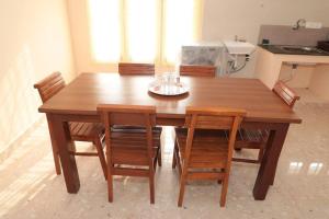 a wooden dining room table with chairs and a kitchen at Soundar villa in Puducherry