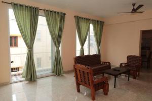 a living room with two chairs and two windows at Soundar villa in Puducherry