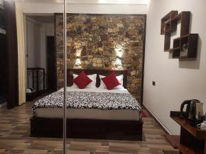 a bedroom with a bed with red pillows and a stone wall at Nine Arch Gap in Ella