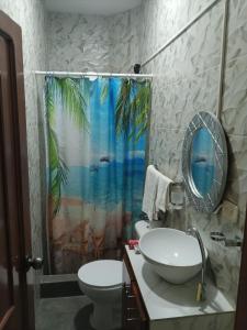 a bathroom with a sink and a palm tree shower curtain at Villa Meyling, Tu Hogar en la Playa Crucita! in Crucita