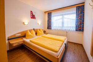 1 dormitorio con 1 cama con sábanas amarillas y ventana en Apartment Bacher Nr.2, en Wald im Pinzgau