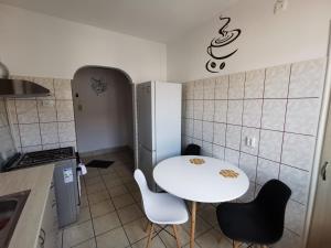eine kleine Küche mit einem weißen Tisch und Stühlen in der Unterkunft Da... dor in Lupeni