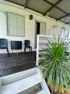 a porch of a house with two chairs and a plant at Tok Abah Cottage in Kota Bharu