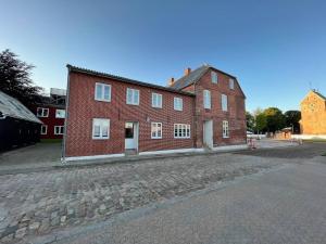 un grande edificio in mattoni rossi su una strada di ciottoli di Town Square Apartments a Højer